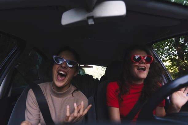 Two happy young women having fun in car Two young women traveling in car singing in car stock pictures, royalty-free photos & images