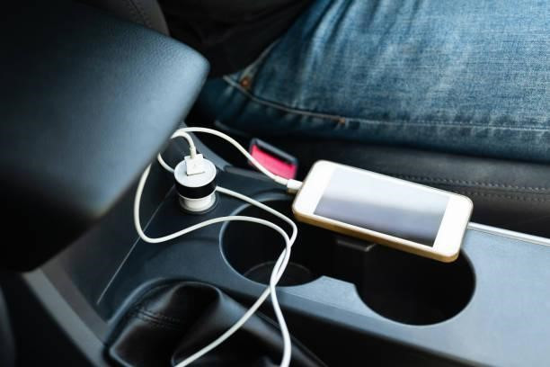 Charging Phone in Car Closeup power socket and adapter charging phone battery on the center console in private care car phone chargers stock pictures, royalty-free photos & images